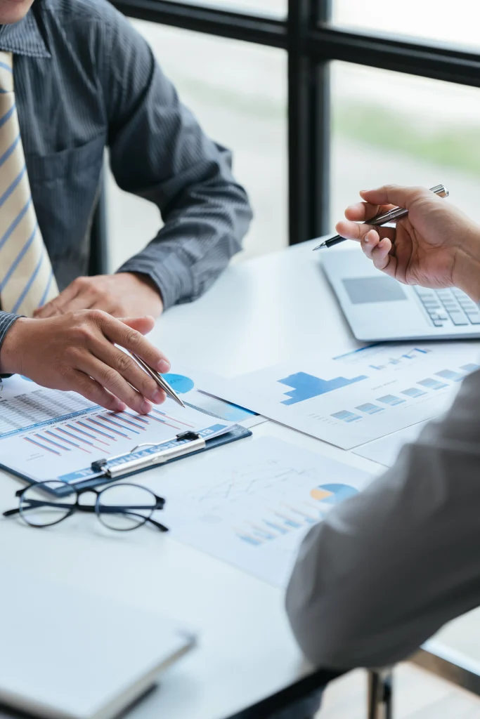 Group of business people meeting, discussing, analyzing graphs, financial data, and planning a marketing project together