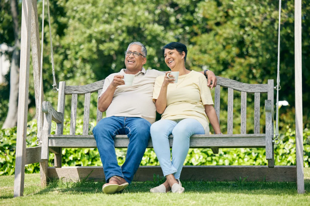Coffee date, bench or old couple in park or nature talking and bonding together in retirement. Senior, elderly man or happy mature woman drinking tea to relax with love, peace or care on fun holiday