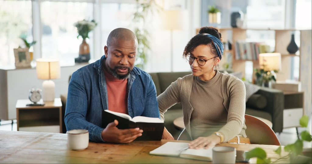 Couple, people and home with reading bible for religious or spiritual guidance, belief and knowledge. Relationship, love and Christians with scripture or verse on holy book to worship and faith