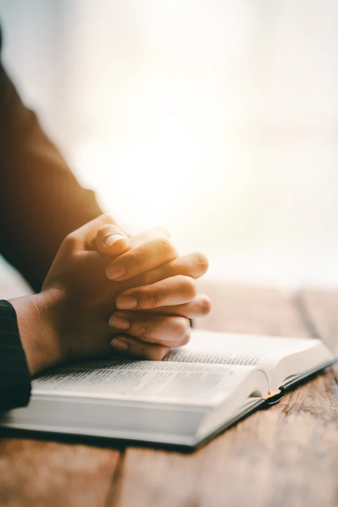 Cropped view of young woman praying with bible on table Confession concept Pray and talk with God