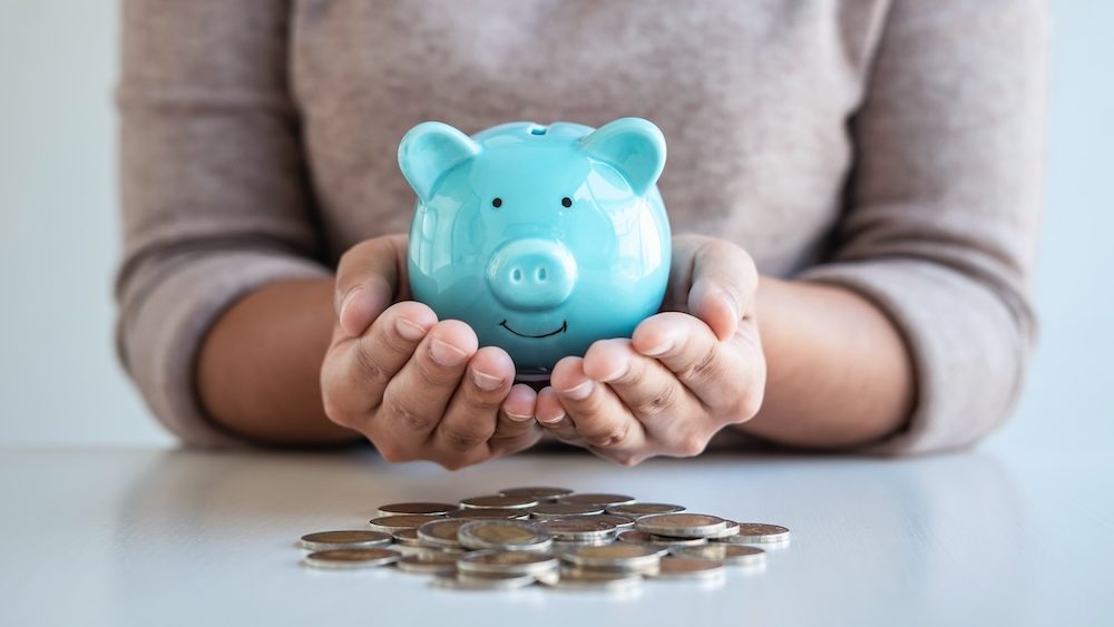 Young woman hands protection piggy bank and planning growing saving to strategy with pile coins for future plan fund of travel, education, home and retirement.